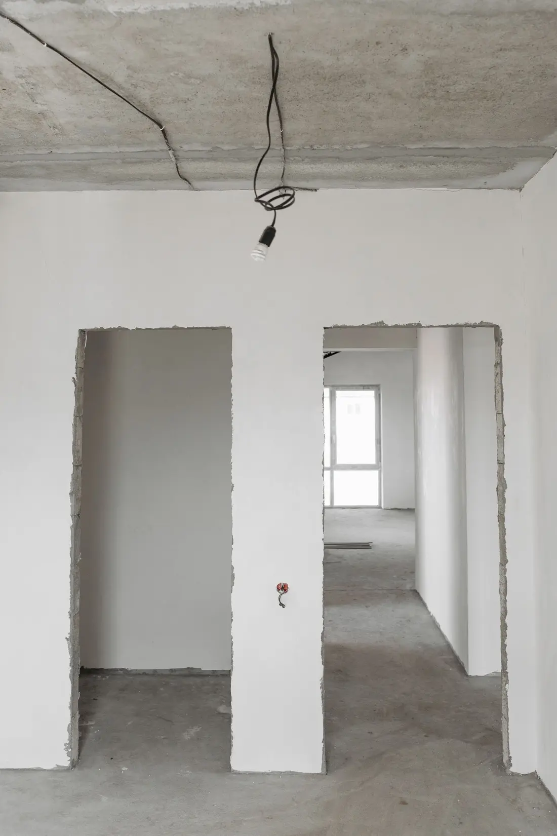 Unfinished interior of a new build with bare concrete floors and freshly plastered walls