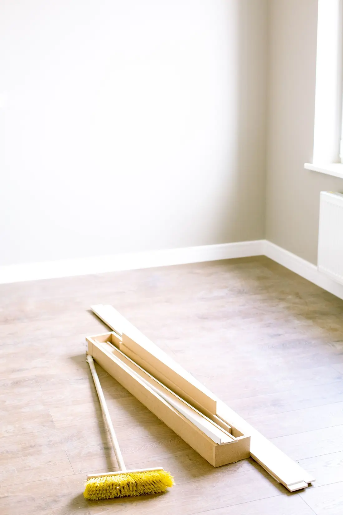Newly installed baseboard trim resting on a new floor at the end of a build