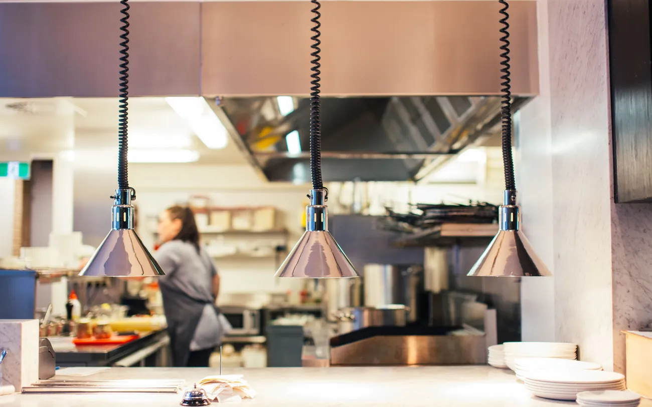 Commercial kitchen service pass with stainless-steel surfaces and heat lamps