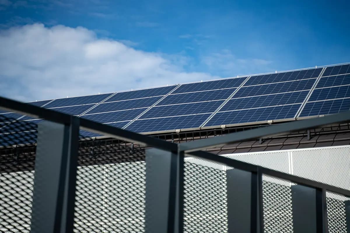 Angled solar panel array mounted on a residential roof against a partly cloudy sky