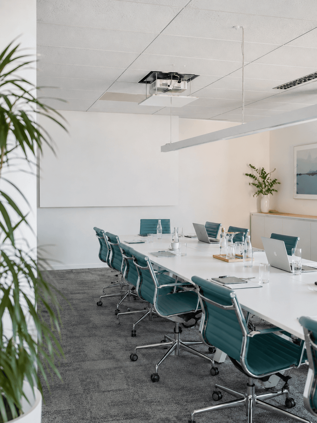 Bright office conference room with a long table and teal chairs