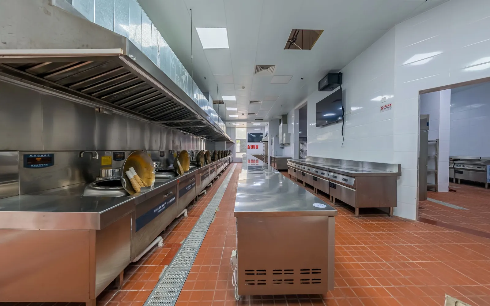 Commercial kitchen floor beside a stainless-steel cook line and equipment exteriors